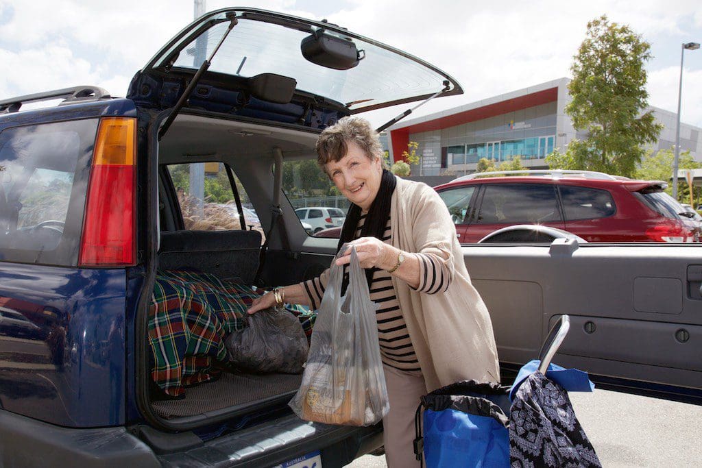 Elderly lady putting shopping bags into the car