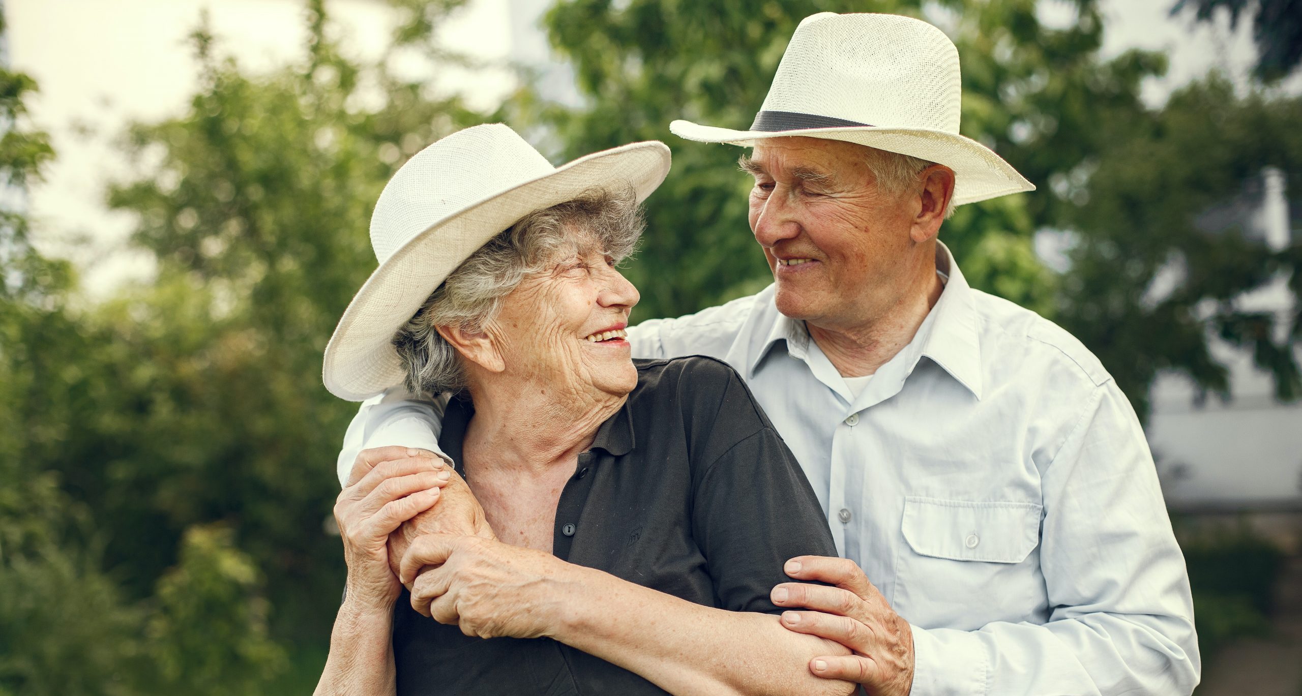 Older couple in hats smiling outside