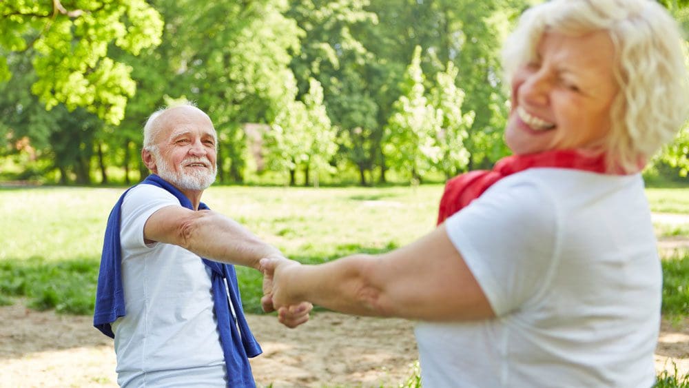 Older couple dancing outside among trees