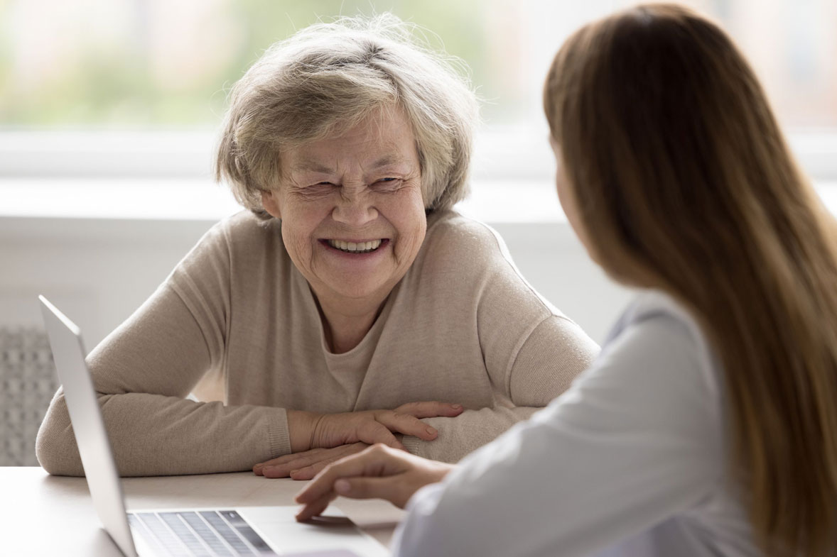 Older woman smiling at a younger woman using a laptop