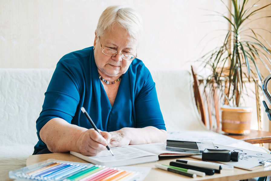 An older woman doing arts and crafts with coloured pens