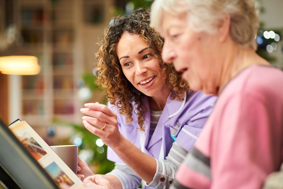 Older woman and support worker looking at a book together